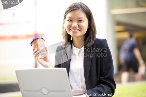 Image of Young Asian female business executive using laptop