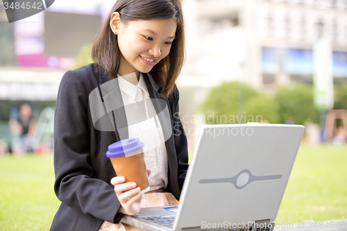 Image of Young Asian female business executive using laptop