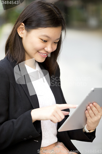 Image of Young Asian female business executive using tablet