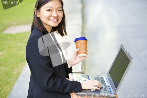 Image of Young Asian female business executive using laptop