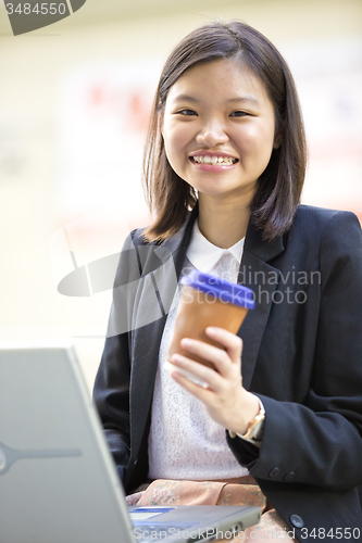 Image of Young Asian female business executive using laptop