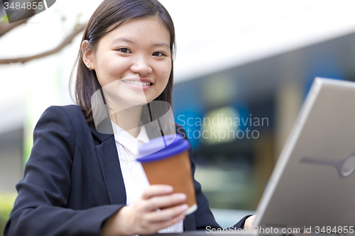 Image of Young Asian female business executive using laptop