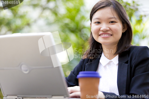 Image of Young Asian female business executive using laptop