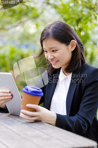 Image of Young Asian female business executive using tablet