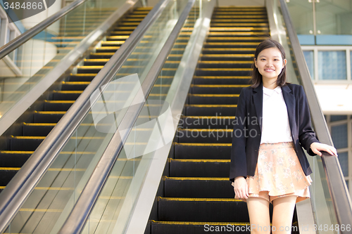 Image of Young Asian female business executive on escalator
