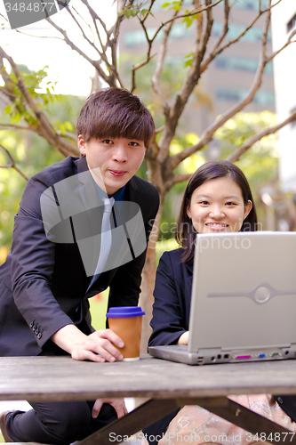 Image of Young Asian female and male business executive using laptop