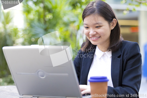 Image of Young Asian female business executive using laptop