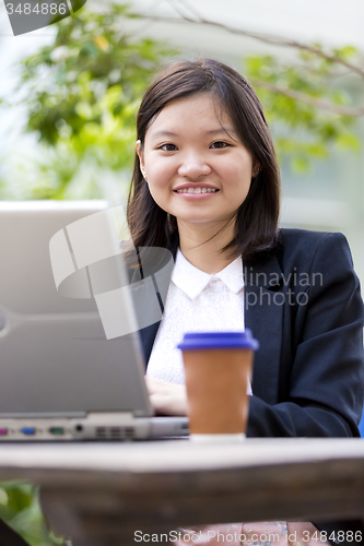 Image of Young Asian female business executive using laptop