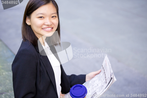 Image of Young Asian female business executive reading newspaper