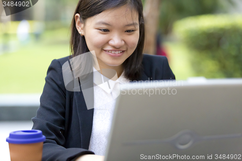 Image of Young Asian female business executive using laptop