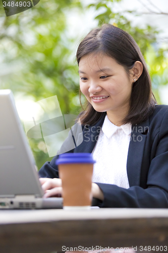 Image of Young Asian female business executive using laptop