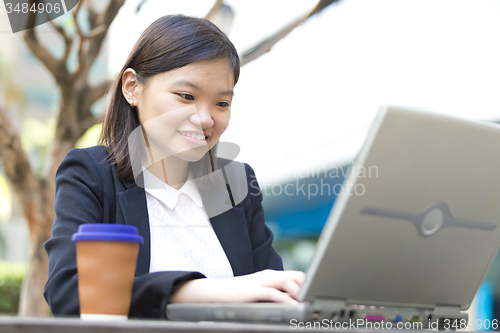 Image of Young Asian female business executive using laptop