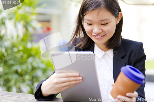 Image of Young Asian female business executive using tablet