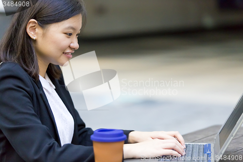 Image of Young Asian female business executive using laptop