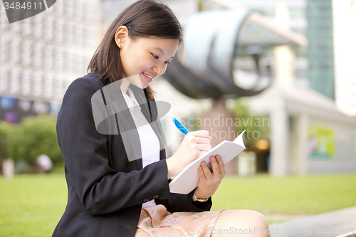 Image of Young Asian female business executive writing on notepad