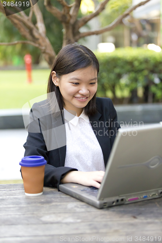 Image of Young Asian female business executive using laptop