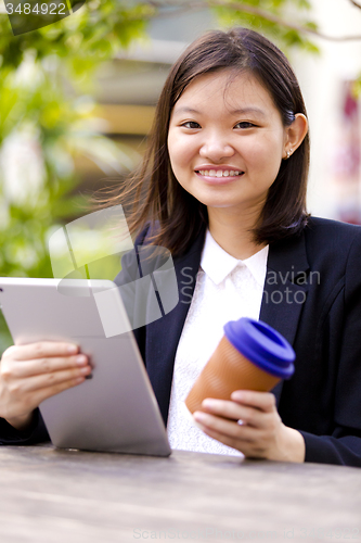 Image of Young Asian female business executive using tablet