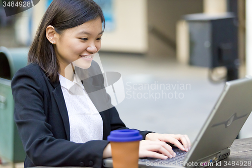 Image of Young Asian female business executive using laptop