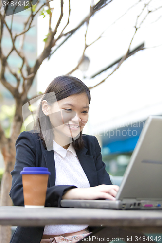 Image of Young Asian female business executive using laptop