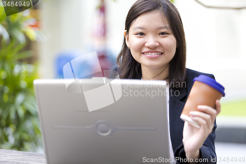 Image of Young Asian female business executive using laptop