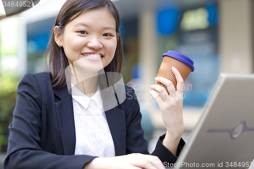 Image of Young Asian female business executive using laptop