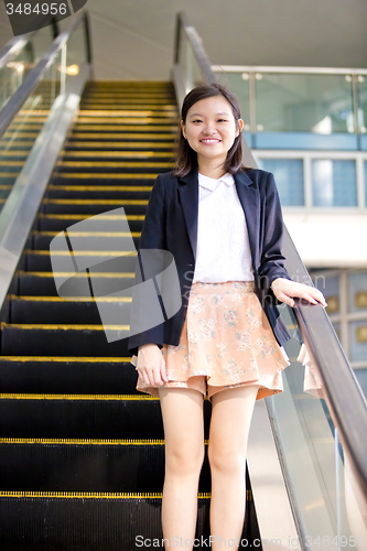 Image of Young Asian female business executive on escalator