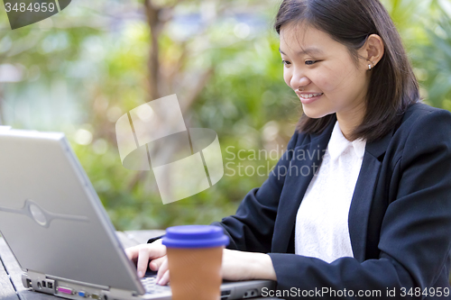 Image of Young Asian female business executive using laptop