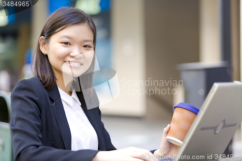 Image of Young Asian female business executive using laptop