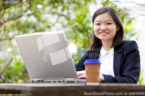 Image of Young Asian female business executive using laptop