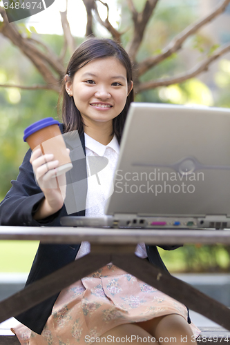 Image of Young Asian female business executive using laptop