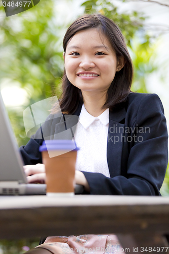 Image of Young Asian female business executive using laptop