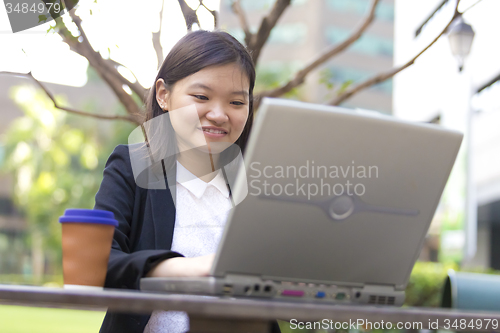 Image of Young Asian female business executive using laptop