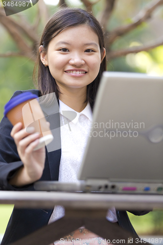 Image of Young Asian female business executive using laptop