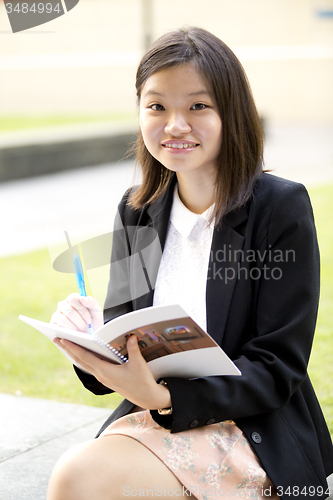 Image of Young Asian female business executive writing on notepad