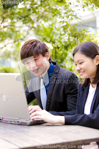 Image of Young Asian female and male business executive using laptop