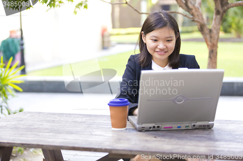 Image of Young Asian female business executive using laptop