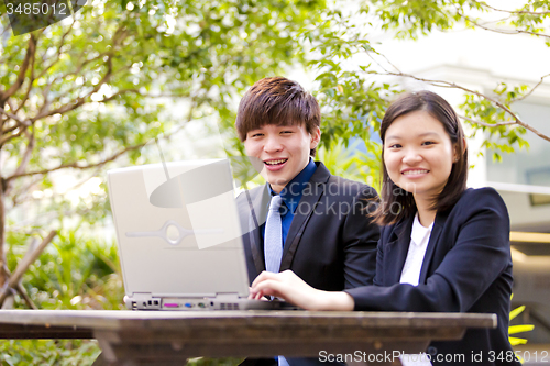 Image of Young Asian female and male business executive using laptop