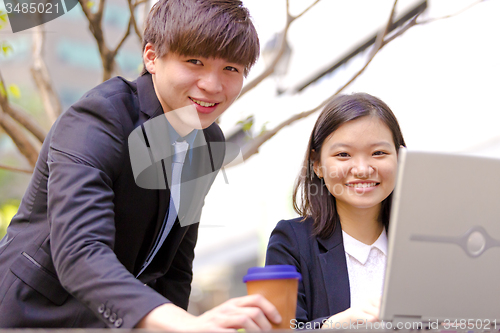 Image of Young Asian female and male business executive using laptop