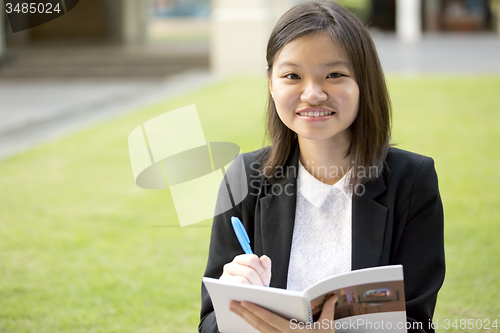 Image of Young Asian female business executive writing on notepad