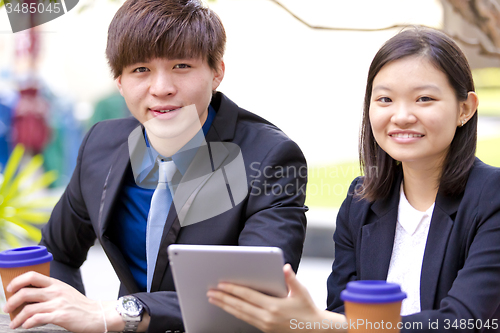 Image of Young Asian female and male business executive using tablet