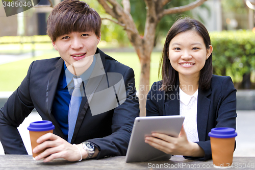 Image of Young Asian female and male business executive using tablet