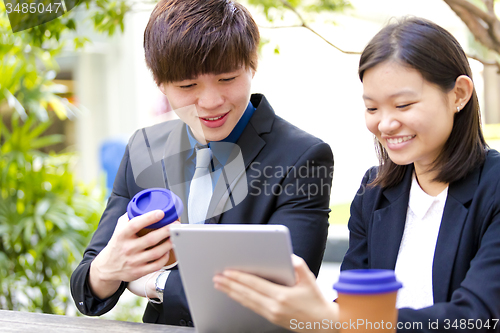 Image of Young Asian female and male business executive using tablet