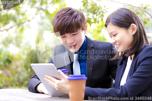 Image of Young Asian female and male business executive using tablet