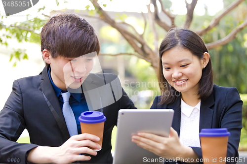 Image of Young Asian female and male business executive using tablet