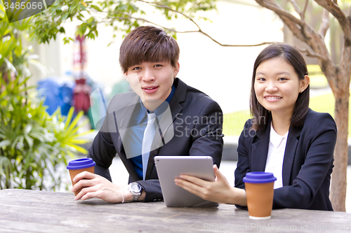 Image of Young Asian female and male business executive using tablet