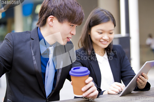 Image of Young Asian female and male business executive using table