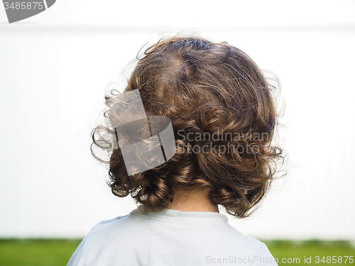 Image of Little caucasian person with curly hair staring at watching a wh