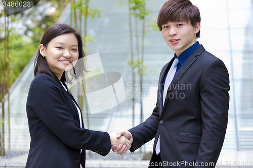 Image of Young Asian female and male business executive shaking hands