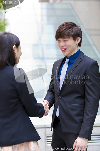 Image of Young Asian female and male business executive shaking hands