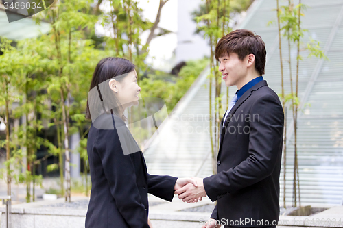 Image of Young Asian female and male business executive shaking hands